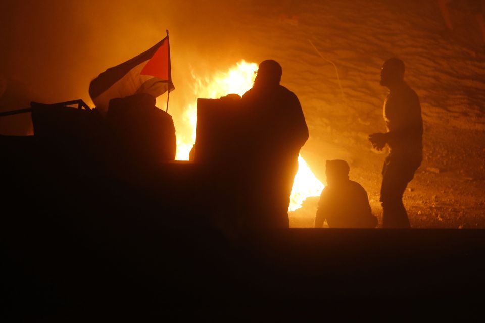 Palestinians stand near a flag of Palestine during an anti-Israel demonstration last night