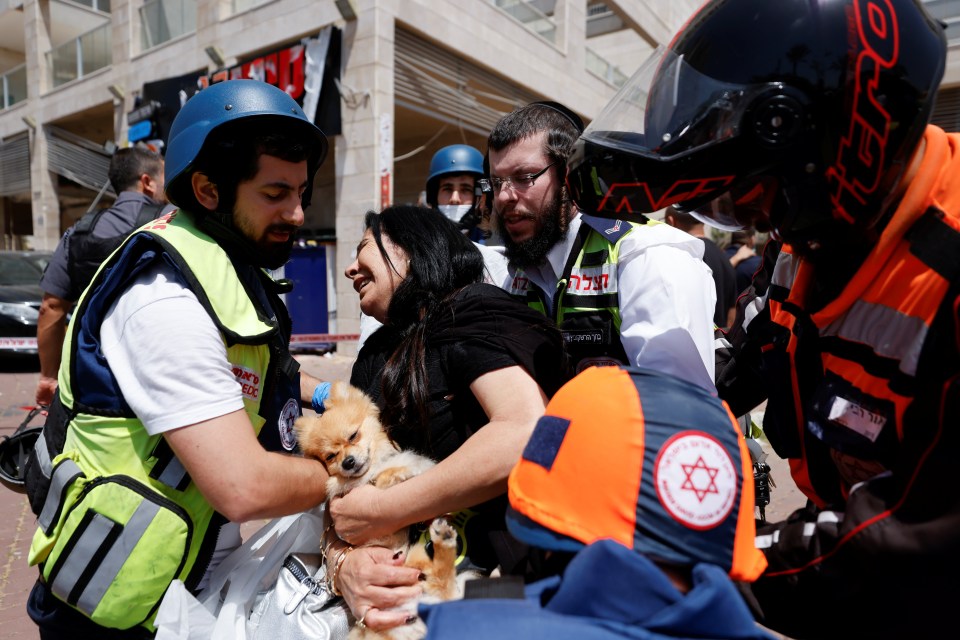 A woman holds her dog as she is evacuated after a rocket hit a shopping complex in Ashkelon, southern Israel