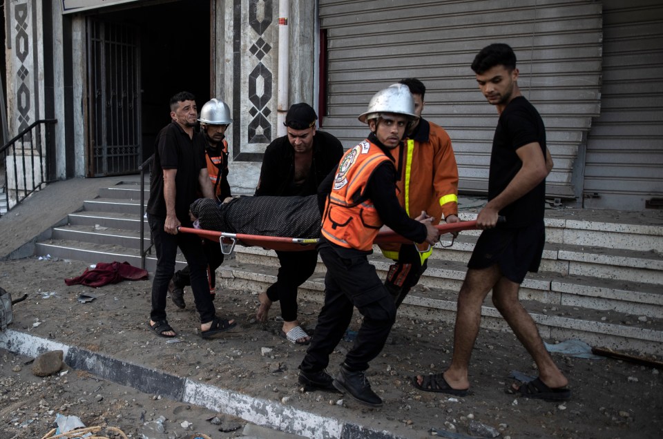 Palestinian rescuers evacuate an elderly woman from a building following Israeli airstrikes on Gaza City