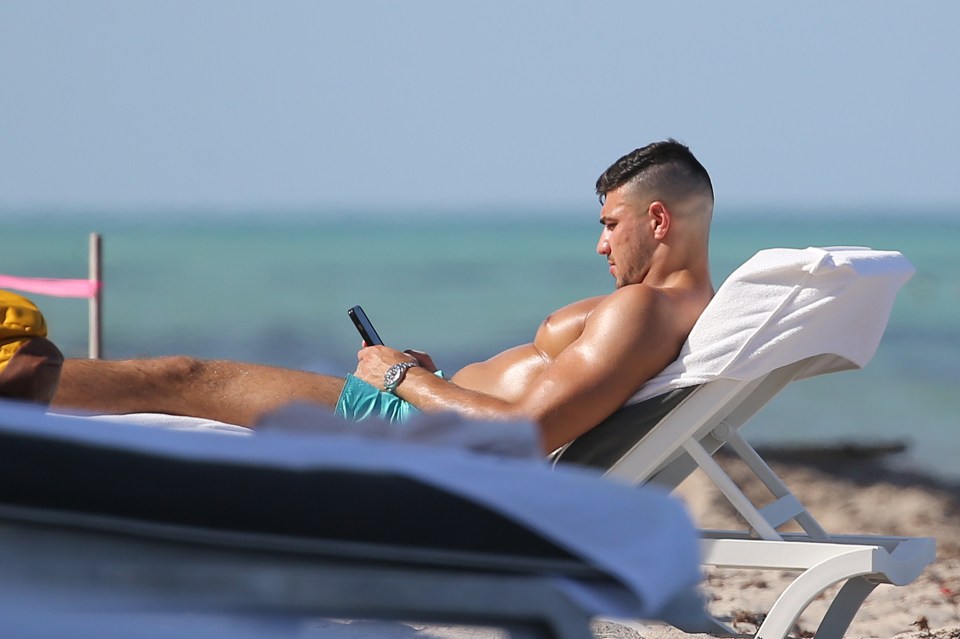 Tommy Fury was glued to his phone as he sunbathed