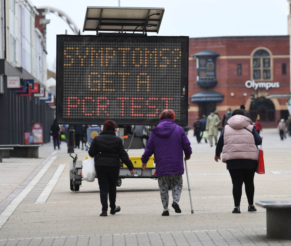 People walking near a warning sign in Bolton - where cases of the Indian variant have soared