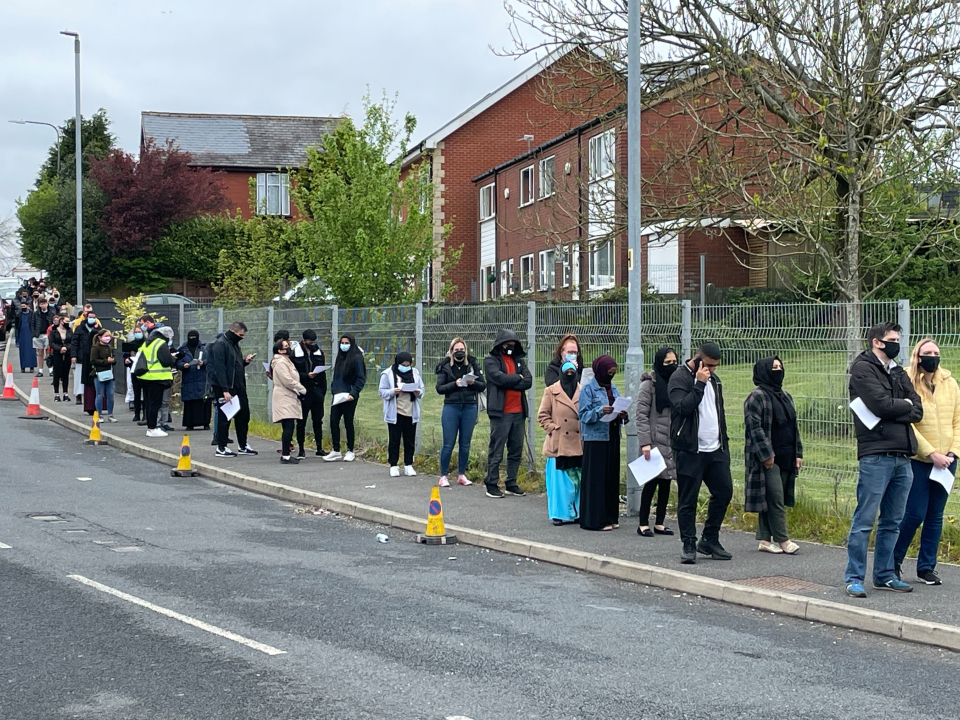 People queue for the vaccination centre at the Essa Academy in Bolton