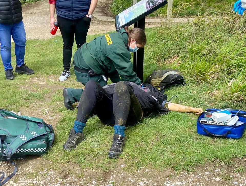 Paramedics attend to the injured woman as she lies flat on the ground after being trampled by the herd of cows