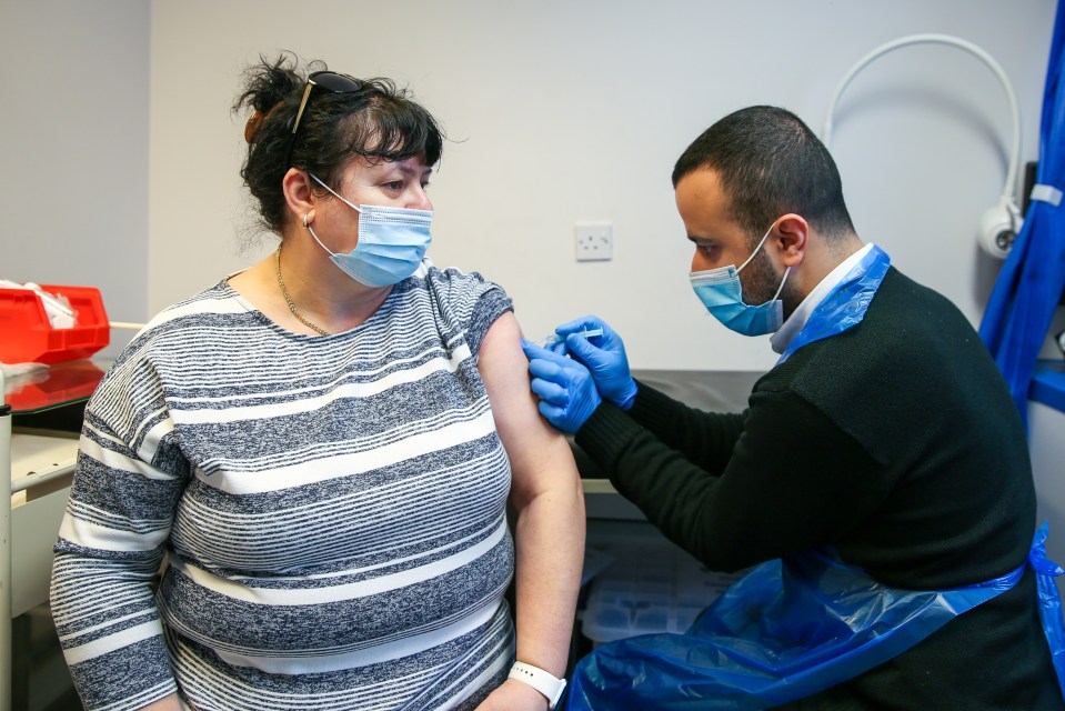 Pharmacist, Huseyin Akpinar administers the AstraZeneca vaccine to Elizabeta Cretu at a vaccination centre in Tottenham, north London, May 23