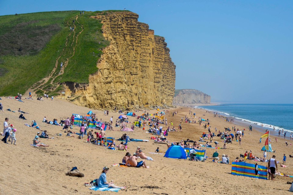 The beach is busy with sunbathers and holidaymakers who flocked to the seaside resort of West Bay in Dorset