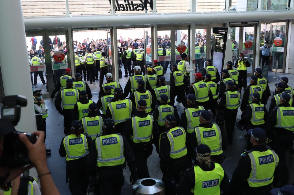 Dozens of police officers gather inside Westfield to stop the mob of anti-vaxxers from entering