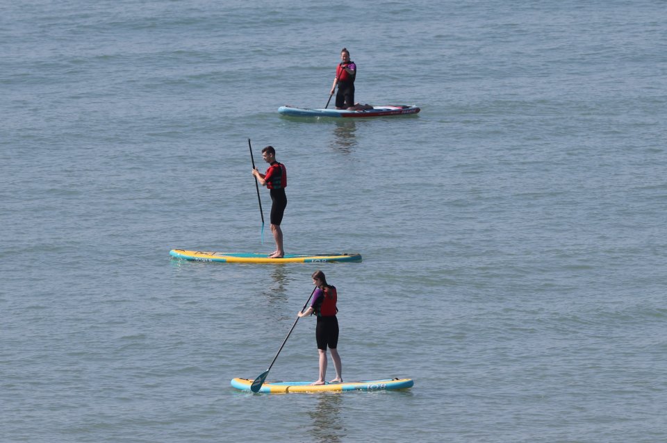 Three friends paddle on Brighton beach