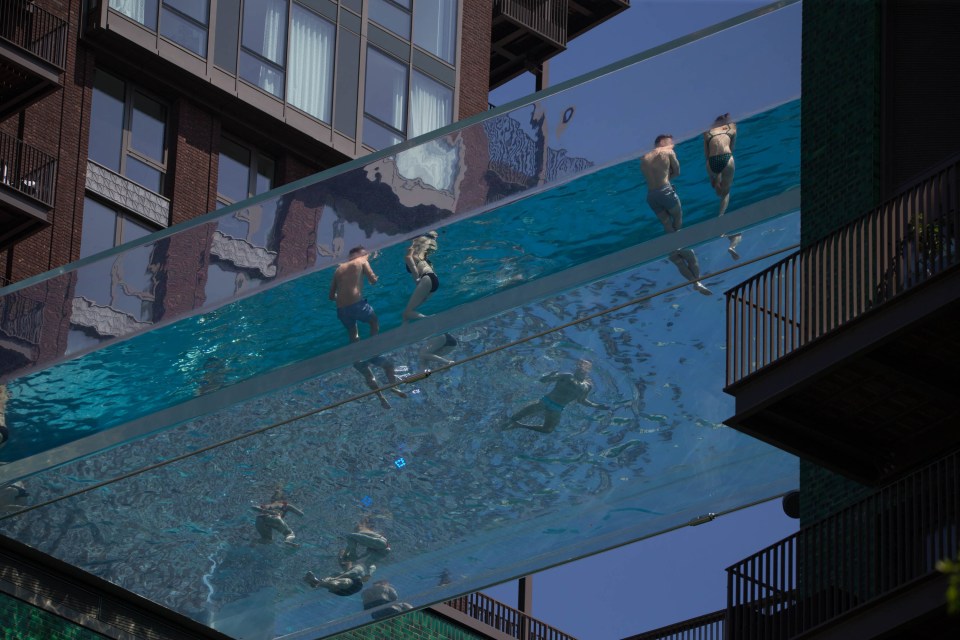 Members of the public are seen in the suspended swimming pool on a sunny day during bank holiday in Embassy Gardens