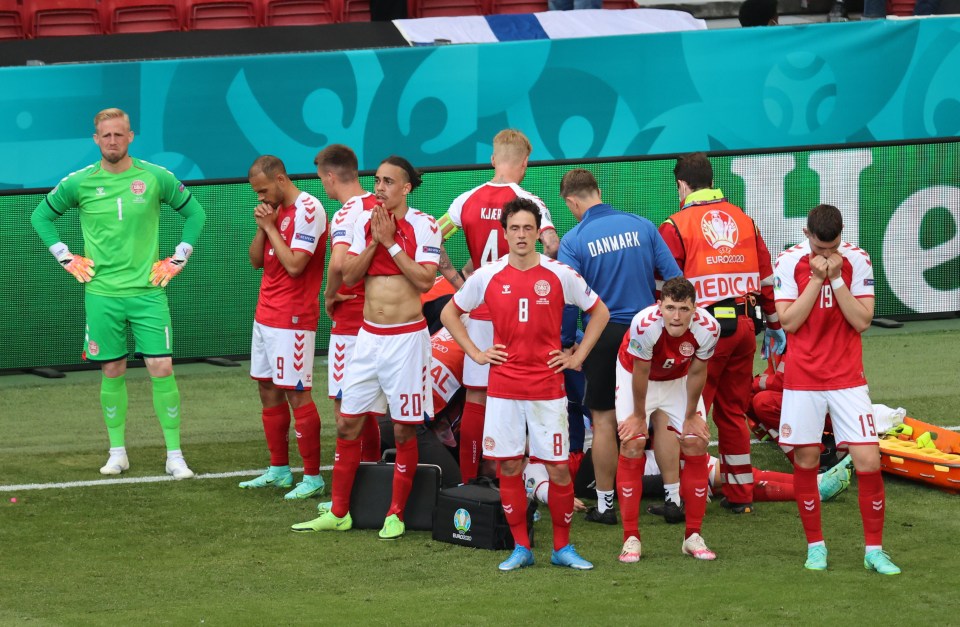 Eriksen’s worried team-mates look on as he receives treatment