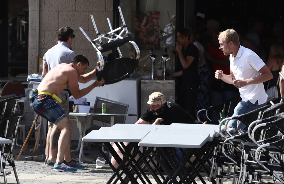 A Russian yob smashes a chair over an England fan as another attacks him on the ground