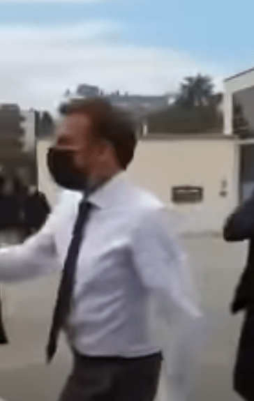 Macron was wearing a white shirt, black tie and a face mask as he greeted the crowd