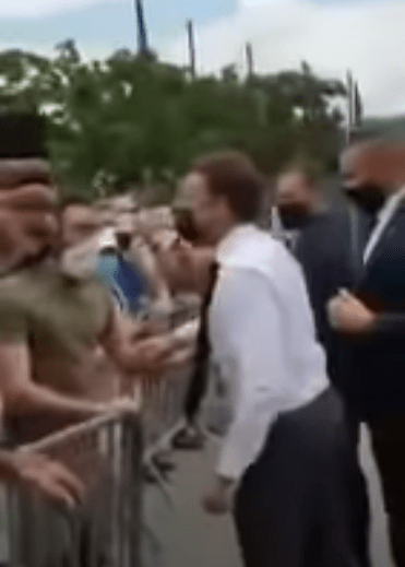 \Macron reached out his hand to greet the man in the green t-shirt before he was slapped