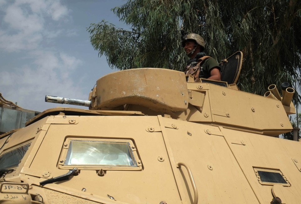 An Afghan soldier stands on a military vehicle as the Taliban encircles the city of Kandahar