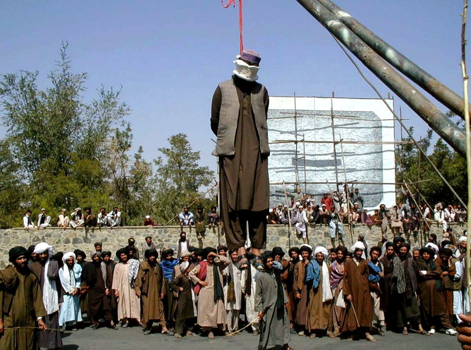 Hundreds of Afghan people gather around a man hanged in the street by the Taliban in 2000