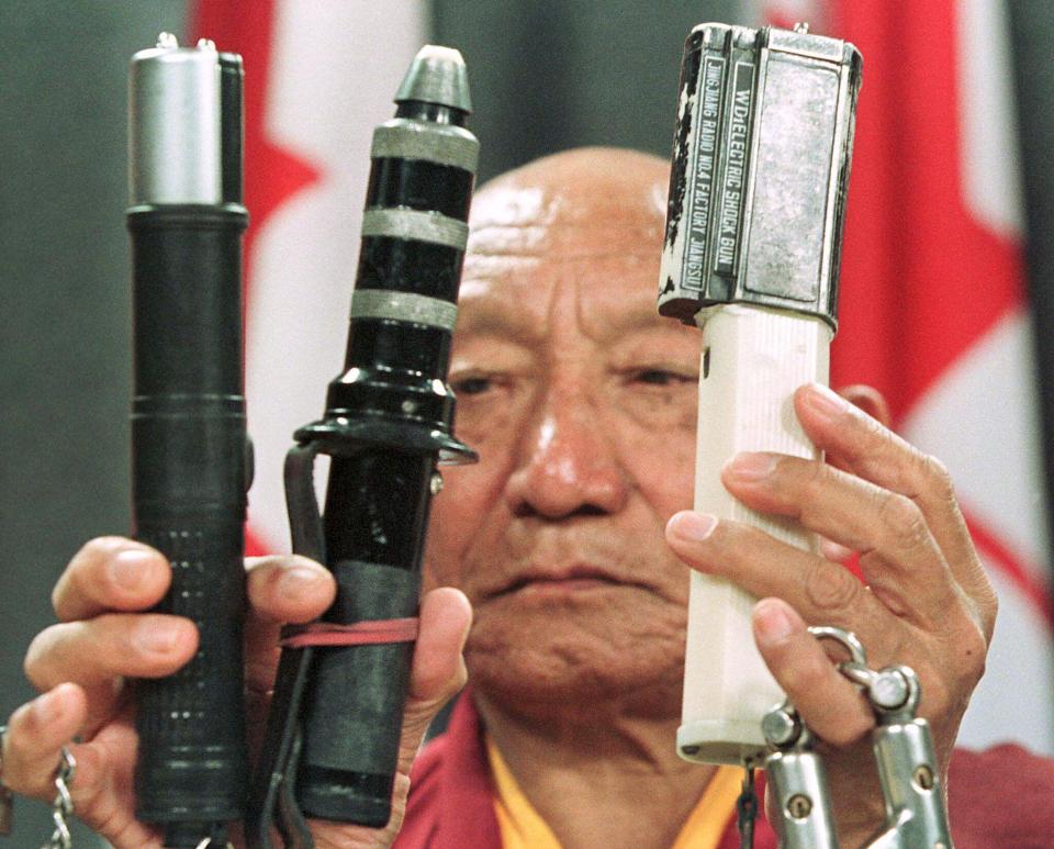 Tibetan Monk Palden Gyatso displays some of the electric torture devices that were used on him in a Chinese jail