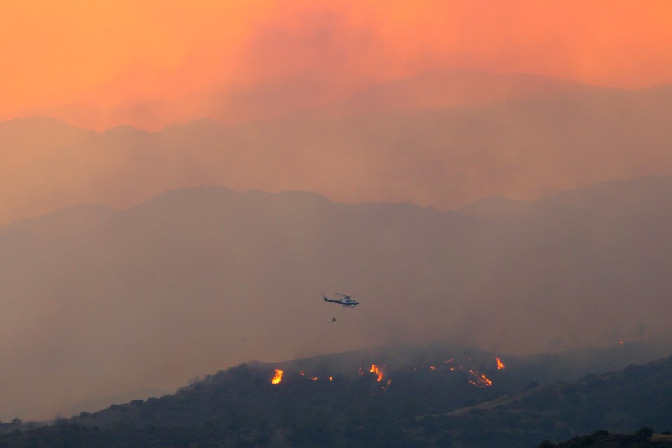 Helicopters fly over the fire