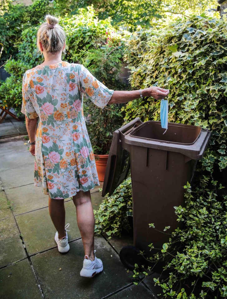 A woman ditches her mask in the bin