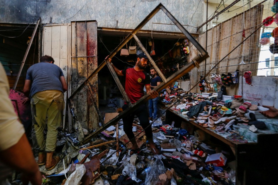 People pick up debris at the site of an explosion in Sadr City district of Baghdad, Iraq, July 19