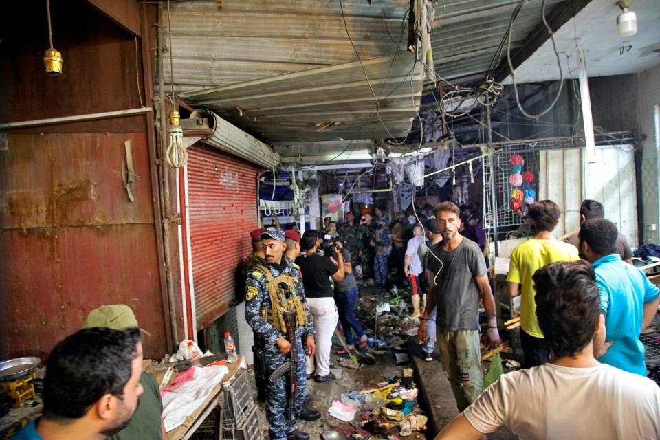 People and security forces gather at the site of a bombing in Wahailat market in Sadr City, Iraq