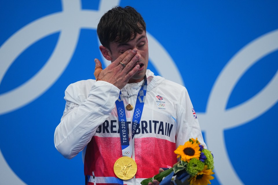 Tom Daley wipes away a tear on the podium after finally winning gold at his fourth time at an Olympics