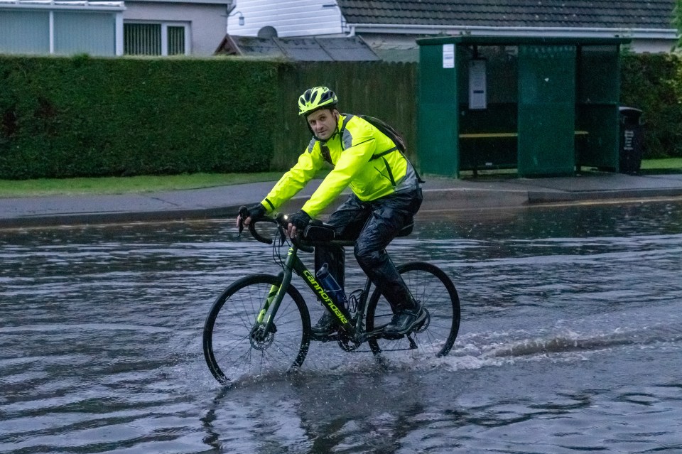 A man riding his bike through flood water in Scotland