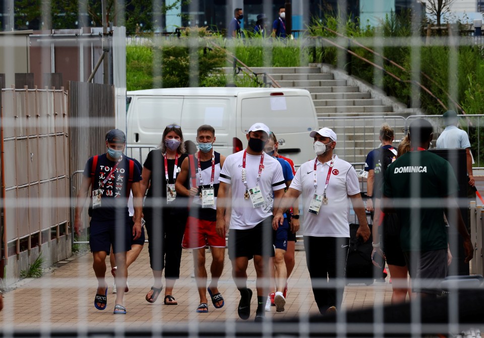 Officials and athletes wear masks inside the Olympic village