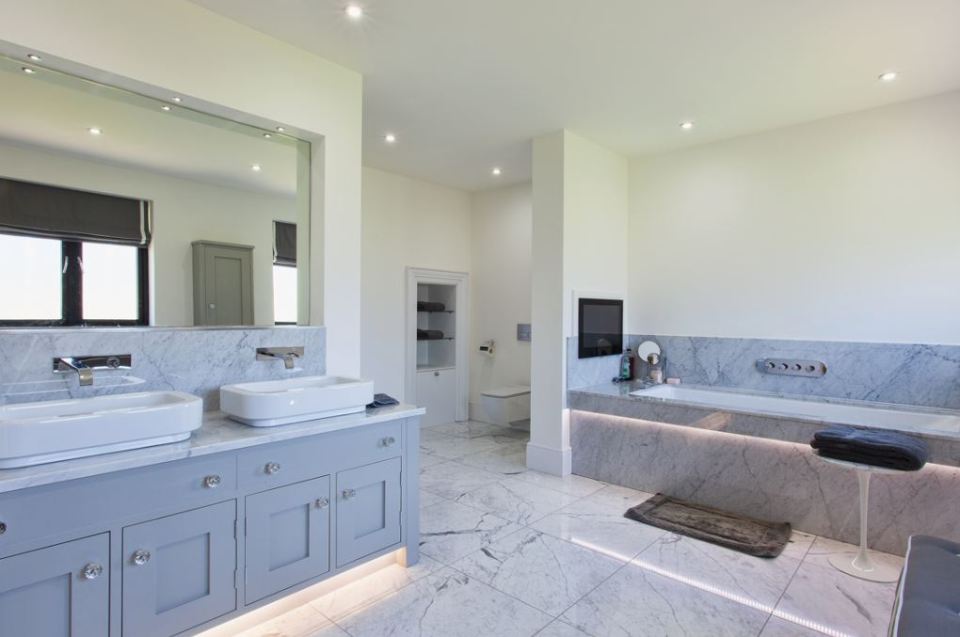 The TV can be seen built-in to the wall at the foot of the luxurious bath