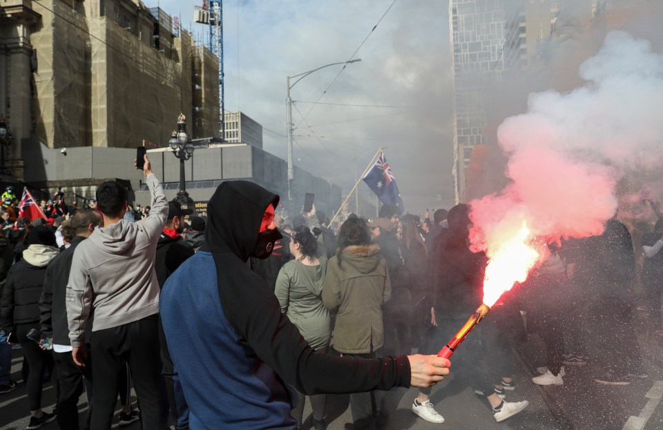 A protester holds a flare in front of Parliament House