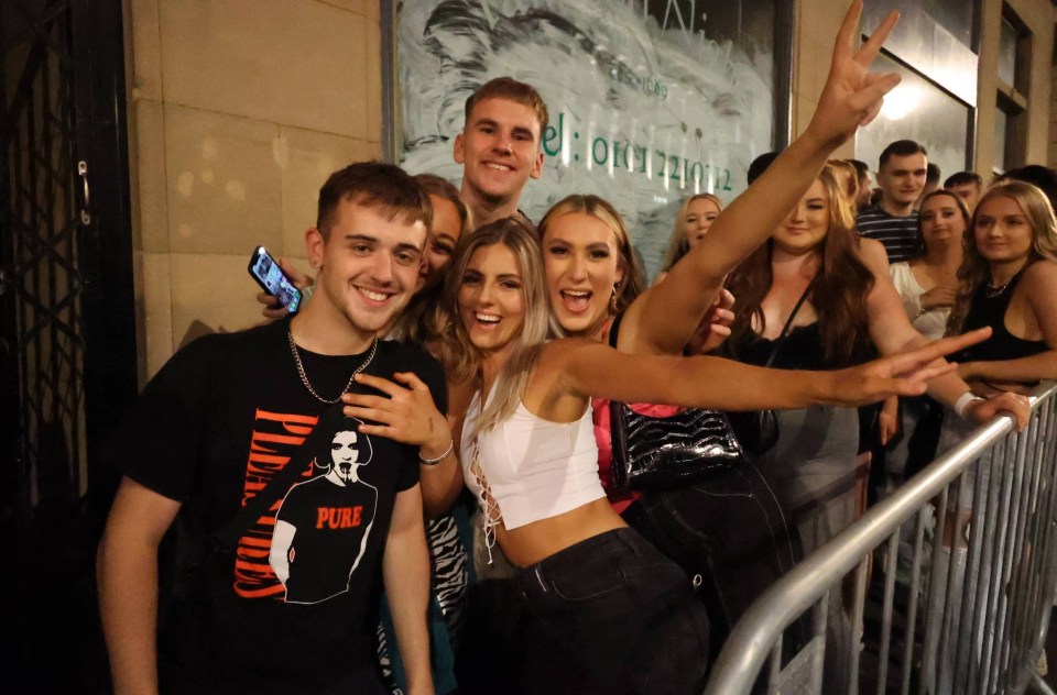 Friends pose outside the nightclub as they wait for it to reopen