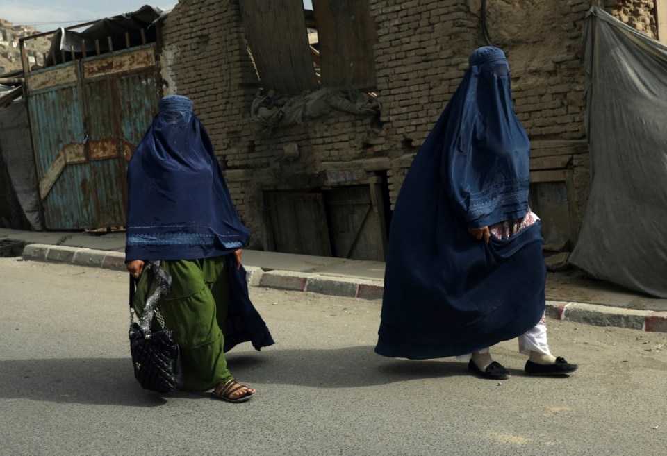 Afghan women in burqas walk on a street in Kabul