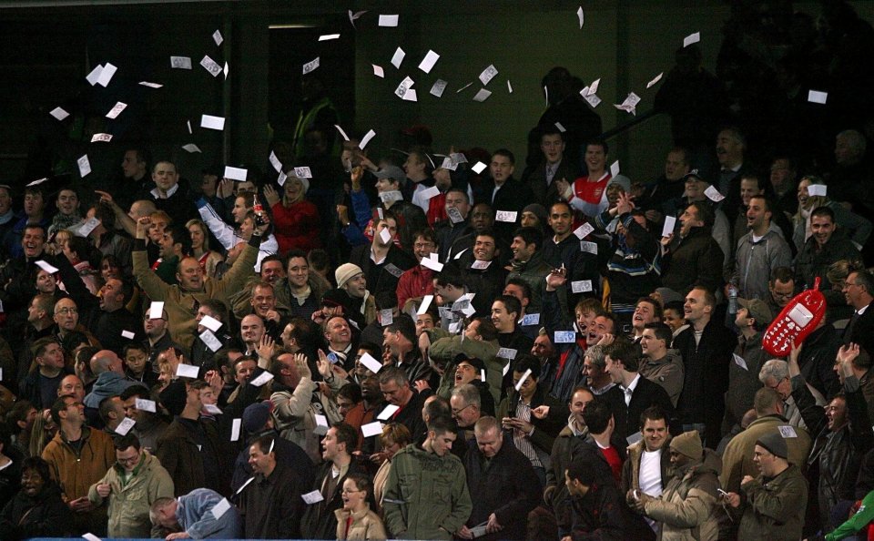 Arsenal fans throw fake bank notes with Ashley Cole's image on them onto the pitch at Stamford Bridge