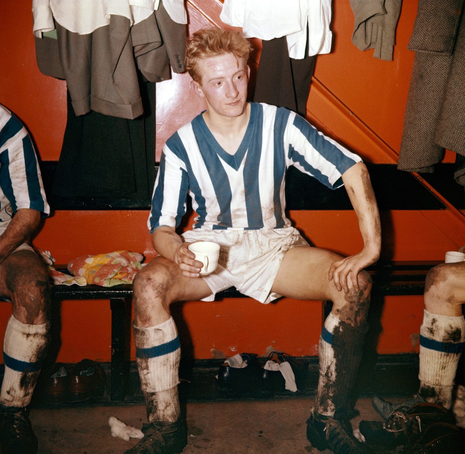 Muddy Huddersfield Town player Denis Law drinks tea after a game.