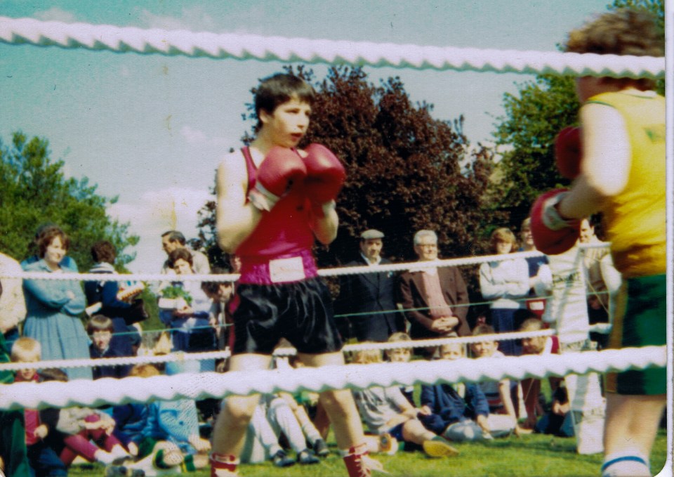 A young Alfie holds up his fists in the boxing ring