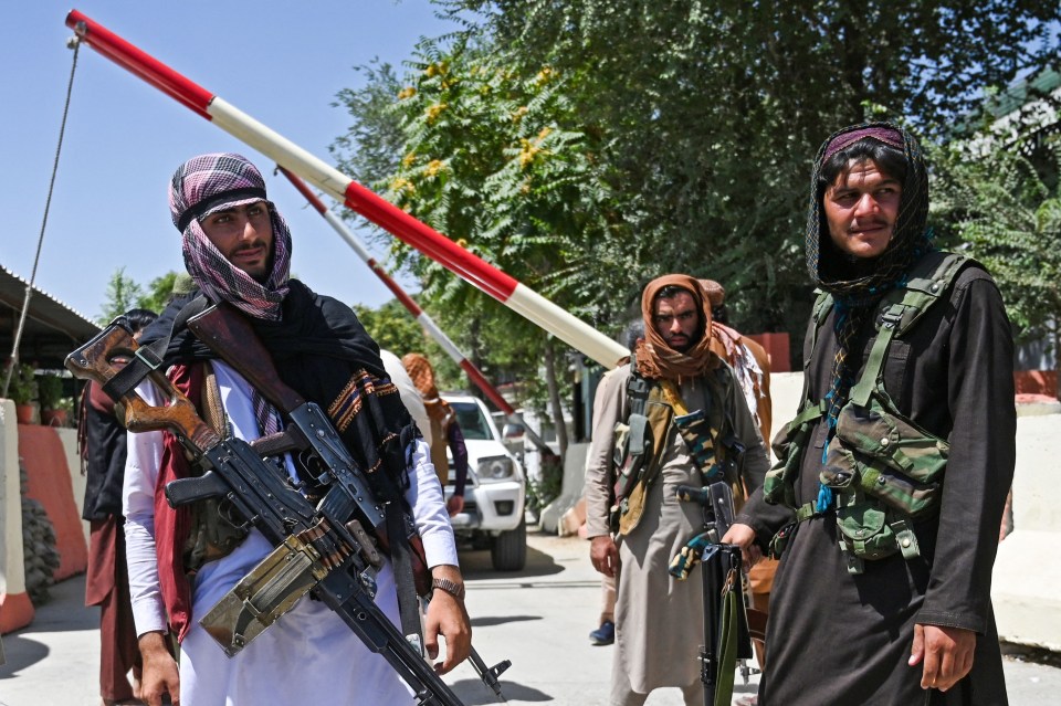 Taliban fighters stand guard in a vehicle along the roadside in Kabul