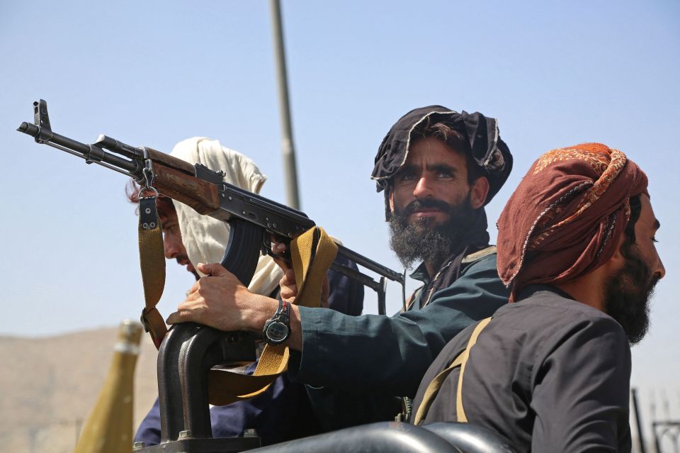 Taliban fighters stand guard in a vehicle along the roadside in Kabul