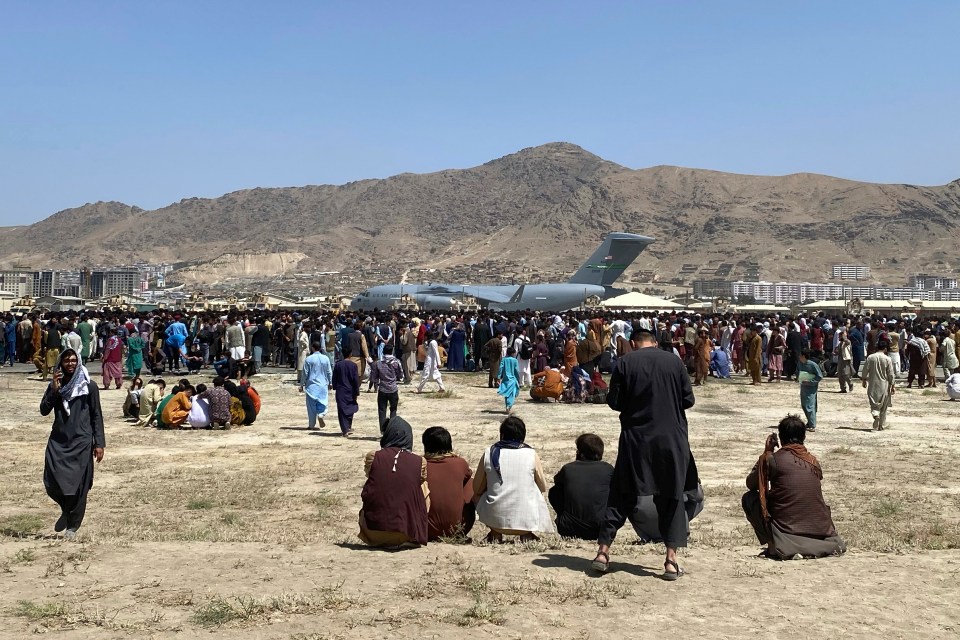 A US Air Force C-17 waits at Kabul airport today watched by hundreds more refugees