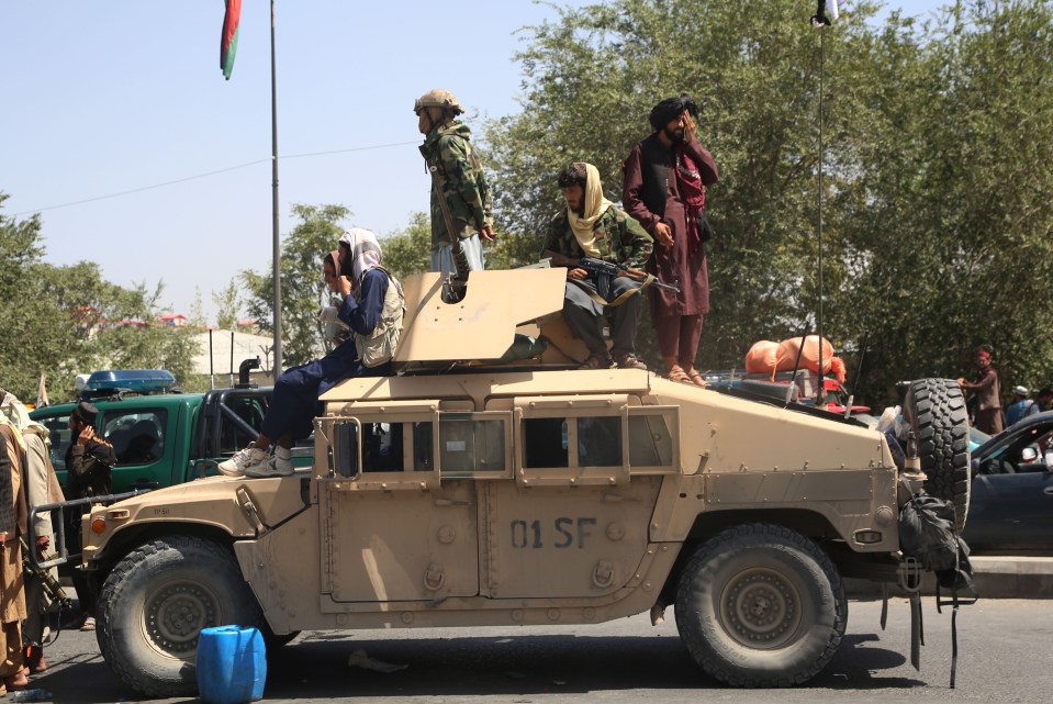 Taliban fighters on patrol in Kabul today in an armoured car left behind by the army