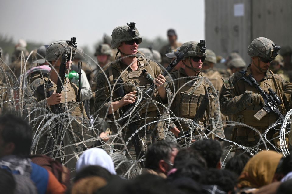 NINTC US soldiers stand guard behind barbed wire at Kabul Airport