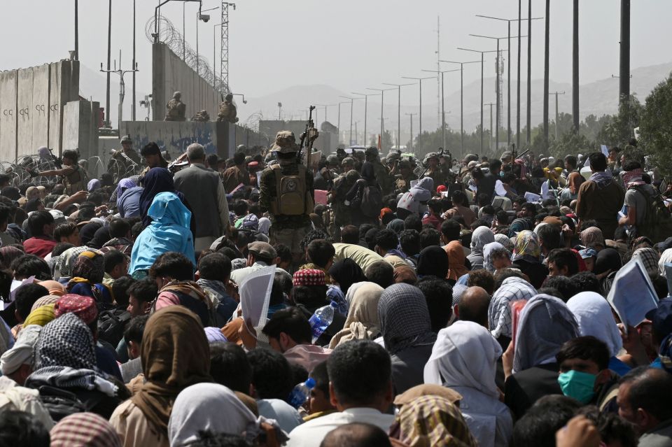 Afghans gather on a roadside near the military part of the airport in Kabul