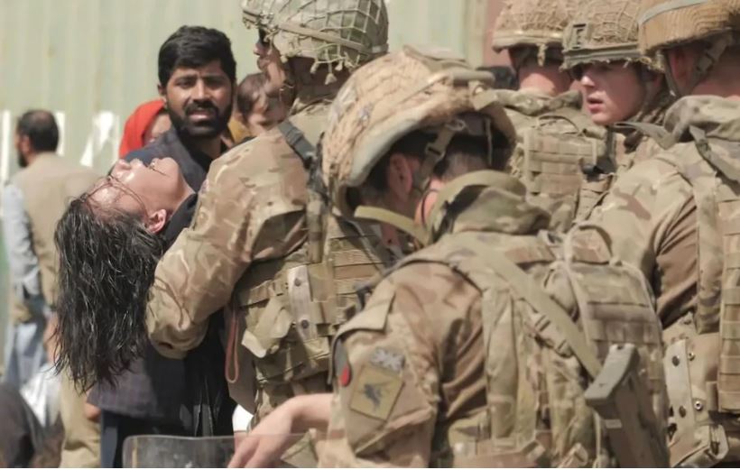 A woman is carried out of the crowd by soldiers