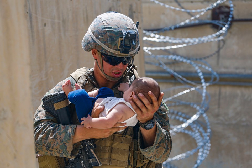 A US Marine carrying a baby - families have reportedly been separated at the airport