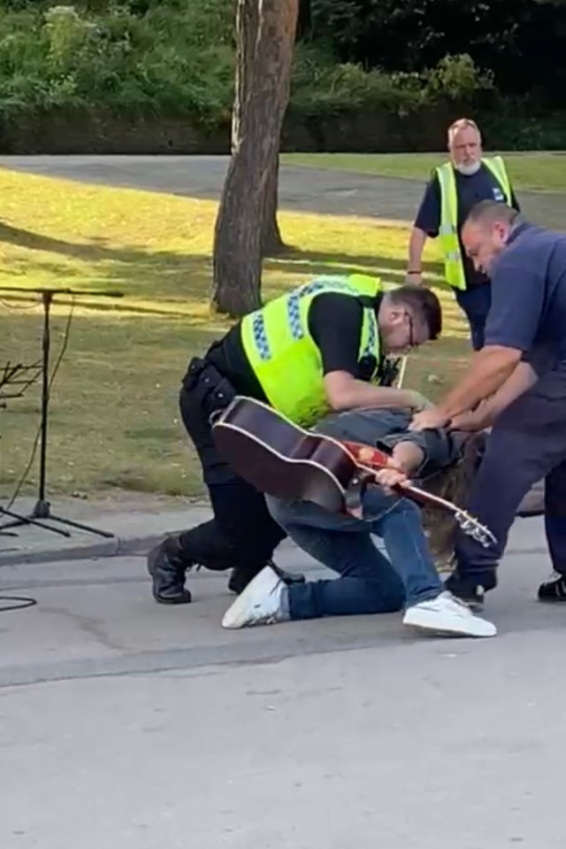 The busker is seen being pinned to the ground