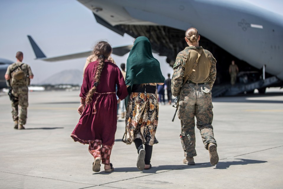 A US Marine walks with a family during ongoing evacuations at Kabul Airport