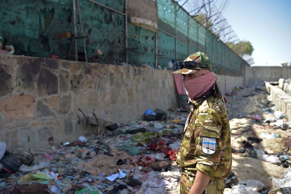 A Taliban fighter stands guard at the site of the suicide bomb blast at Kabul airport