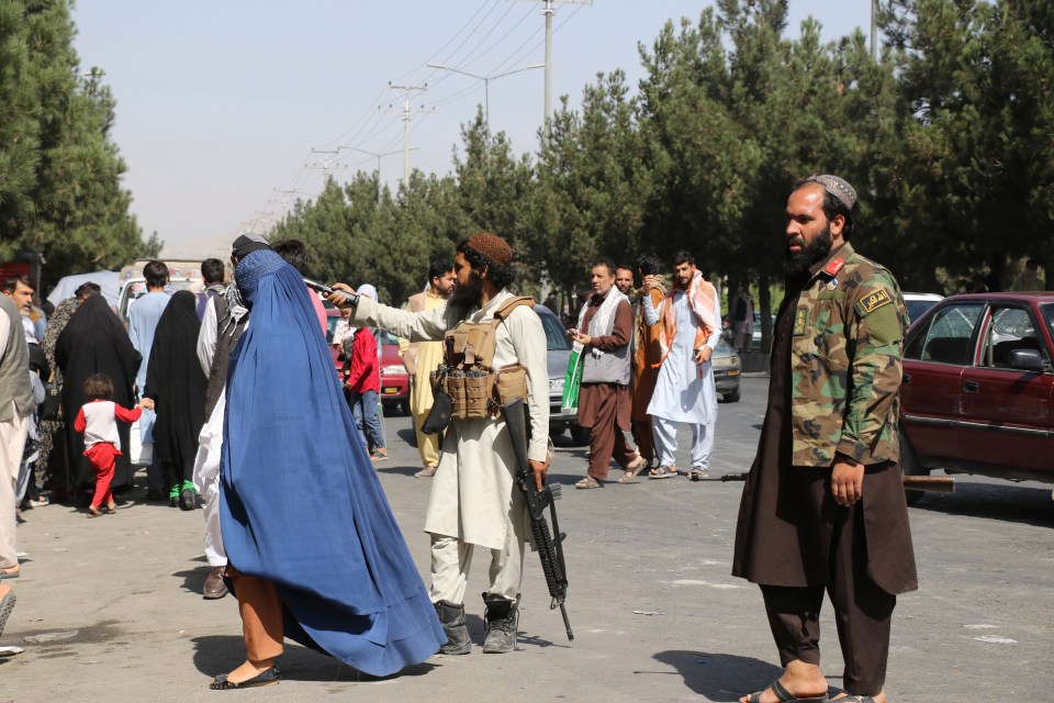 Taliban fighters keep a crowd outside Kabul airport moving on