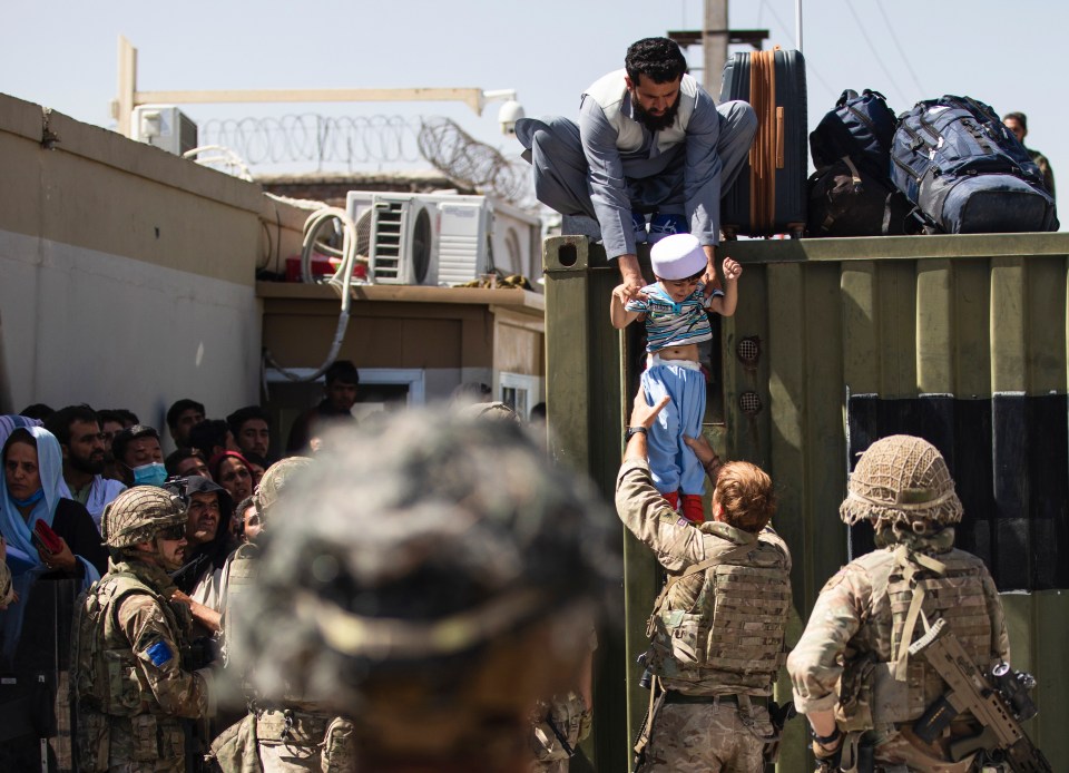 An Afghan man hands his child to a British Paratrooper amid the chaos at Kabul airport