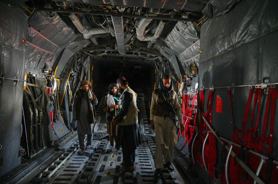 Taliban fighters walk inside an Afghan Air Force aircraft