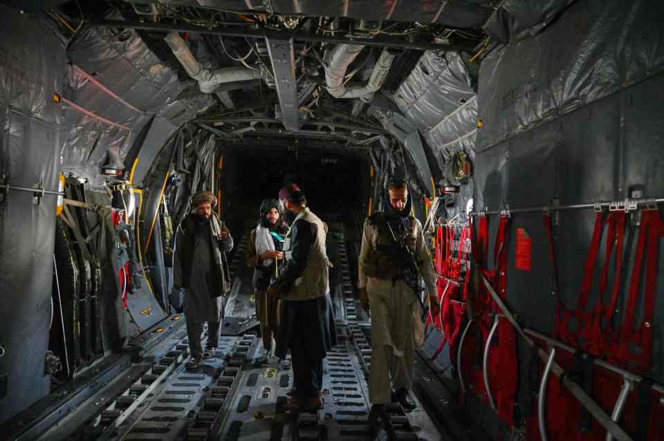 Taliban fighters walk inside an Afghan Air Force aircraft