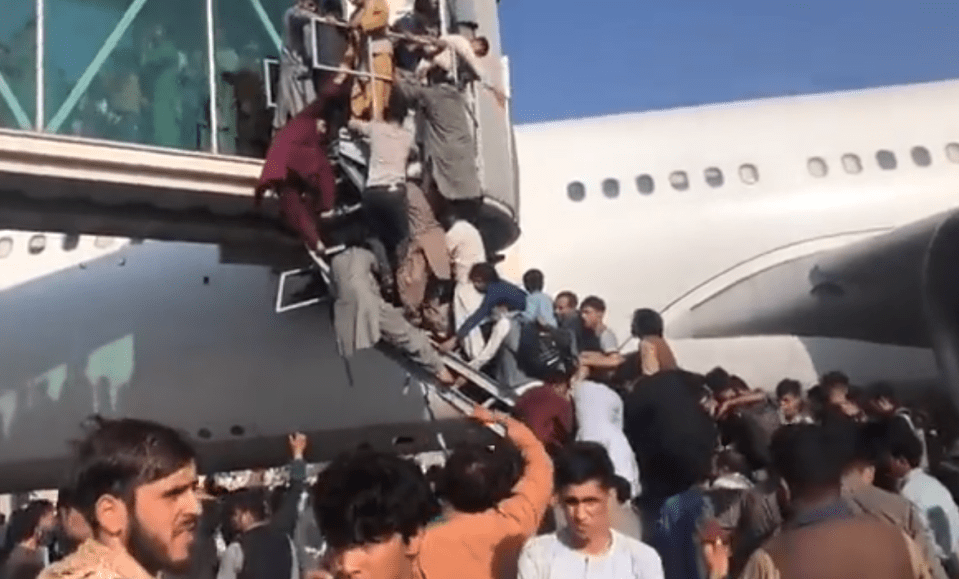 Desperate Afghans climb stairs in a bid to get onto the aircraft