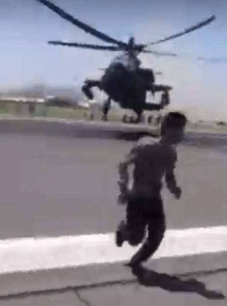 A US helicopter swoops across the runway to clear the way for a plane to take off